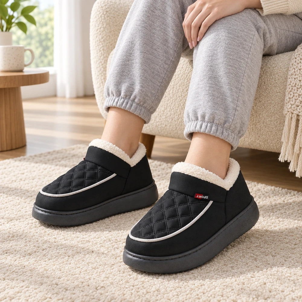 Chaussons d'intérieur MOÉLIA noirs portés dans un salon lumineux Image