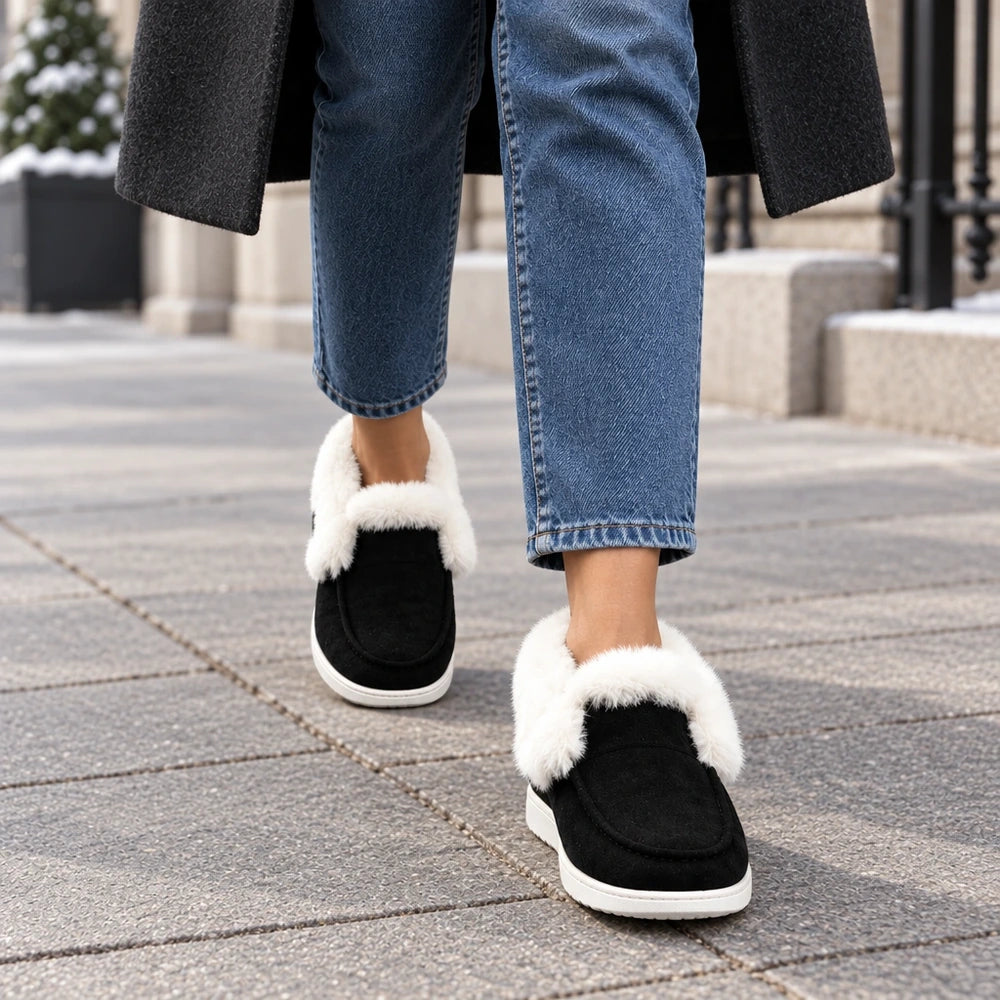 Boots fourrées noires Orthopodys en suède avec col en peluche blanche et semelle plateforme, portées en extérieur.