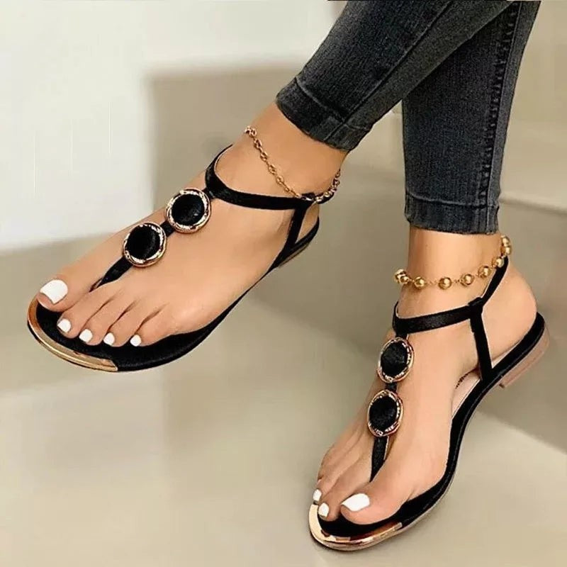 Sandales femme Orthopodys, marque exploitée par AIIBORI (SASU), noires plates avec détails dorés et bride cheville