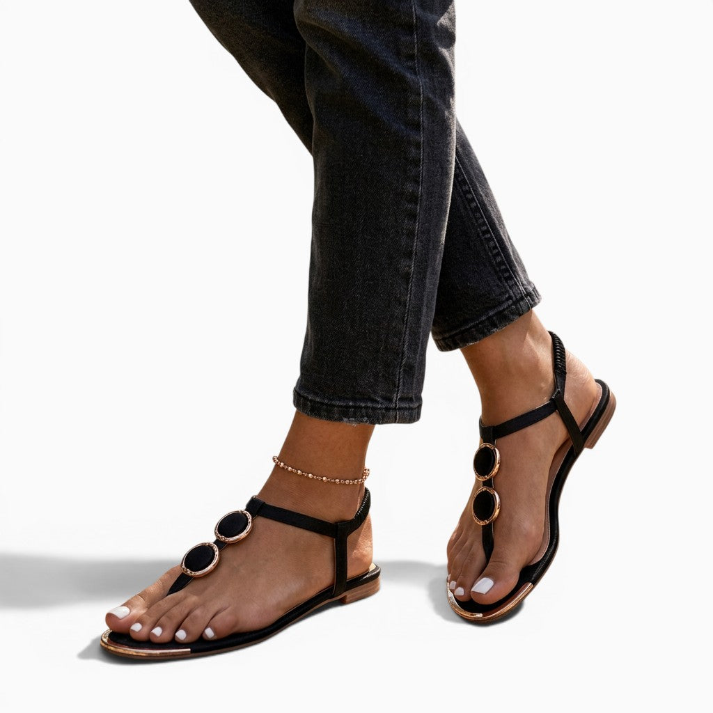Sandales femme Orthopodys, marque exploitée par AIIBORI (SASU), noires plates avec détails dorés circulaires en extérieur
