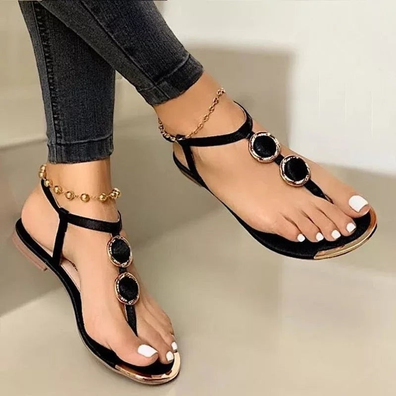 Sandales femme Orthopodys, marque exploitée par AIIBORI (SASU), noires plates avec détails dorés et bride cheville