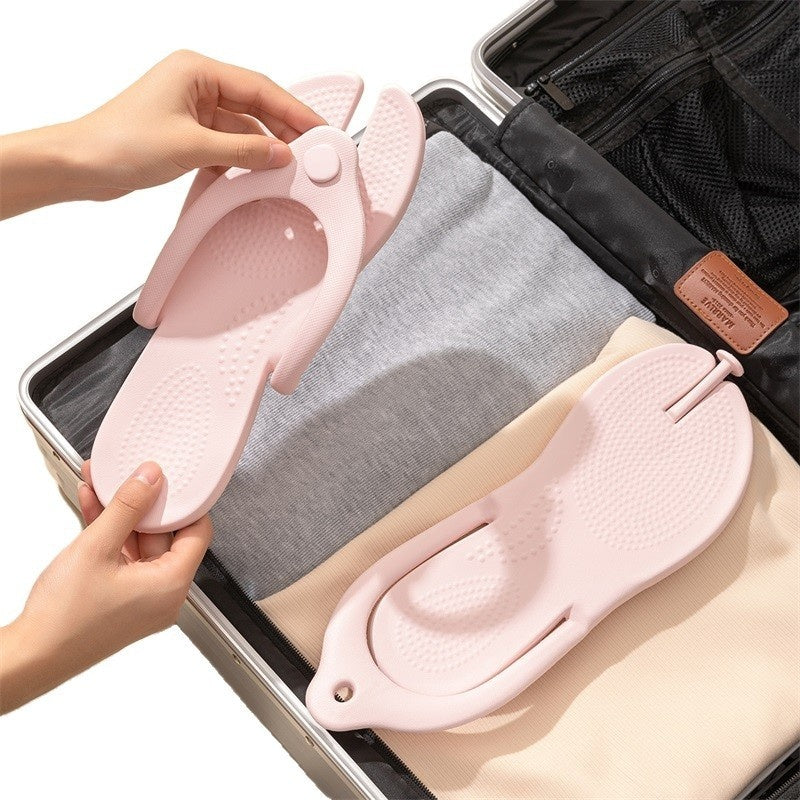 Mains tenant une tong pliable rose NOMADYS par Orthopodys, marque exploitée par AIIBORI (SASU) dans une valise ouverte.