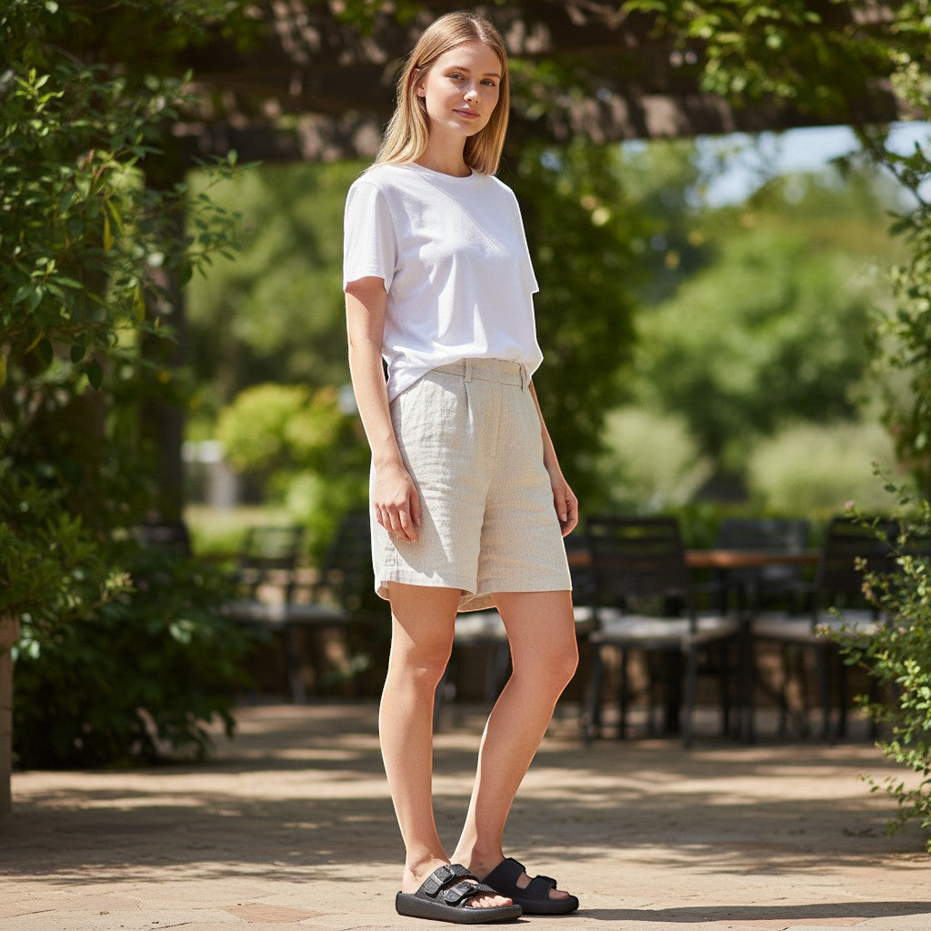Femme portant des mules Orthopodys NELYA noires à double bride réglable et semelle plateforme dans un jardin ensoleillé