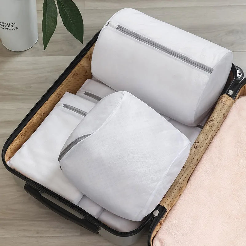 Sacs de lavage pour chaussures MAILLYS™ par Orthopodys en maille blanche cylindrique rangés dans une valise ouverte