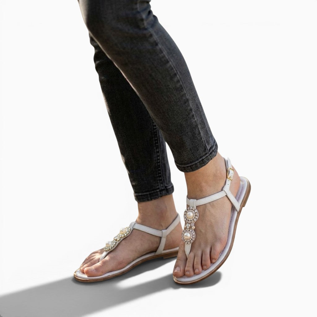 Sandales femme Orthopodys Riviera blanches plates avec ornements perles portées avec un jean gris en extérieur