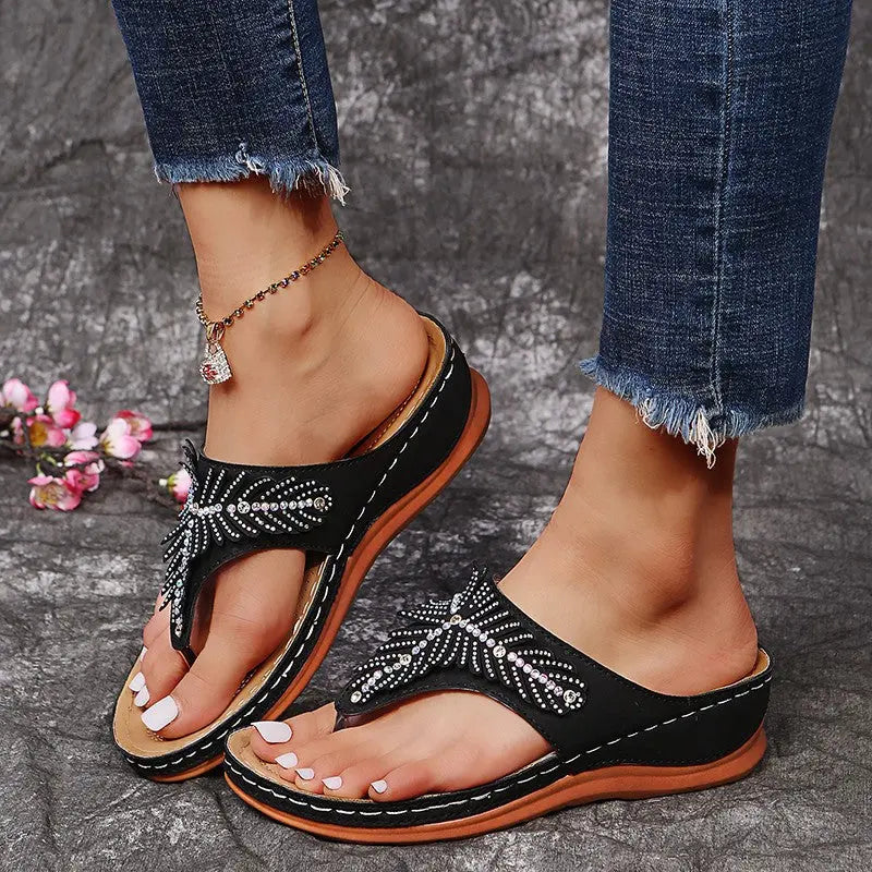 Sandales SÉLYNA™ noires portées – détail de la semelle compensée